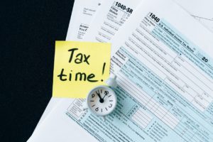 מסמכי מיסים ועליהם שעון ופתק עליו כתוב זמן מיסים